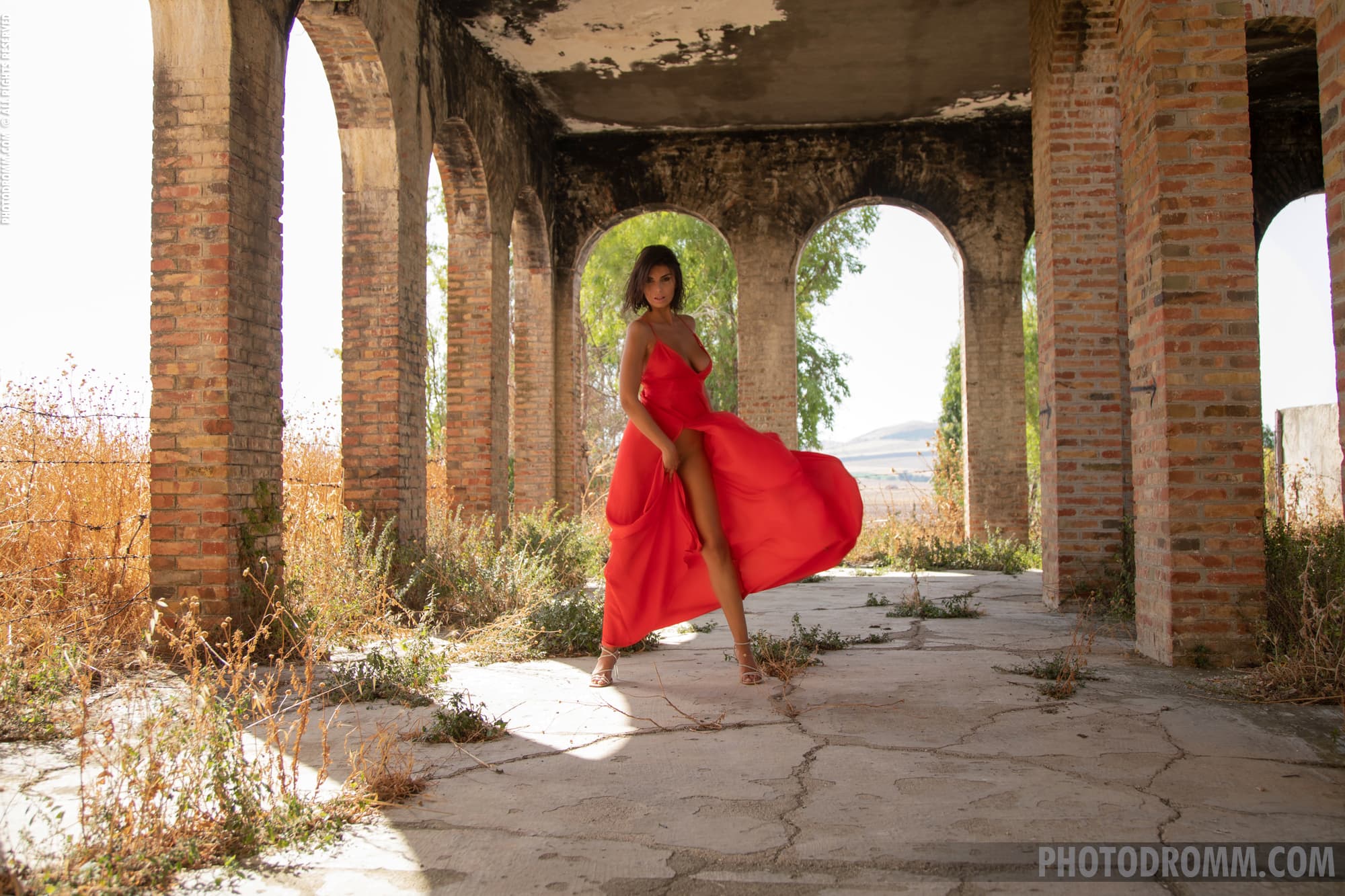 Giselle poses seductively as she slowly removes her red dress outdroors