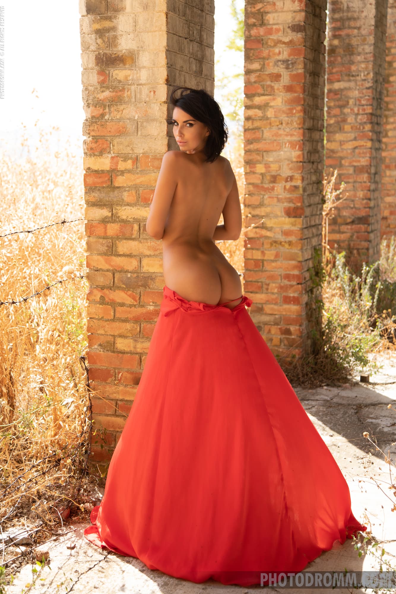 Giselle poses seductively as she slowly removes her red dress outdroors
